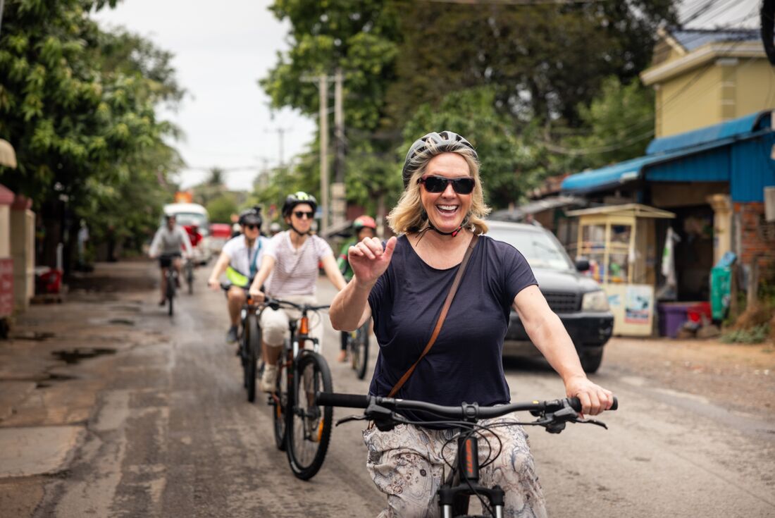 Traveller smiling and waving at camera while on a bicycle tour in Battambang, Cambodia