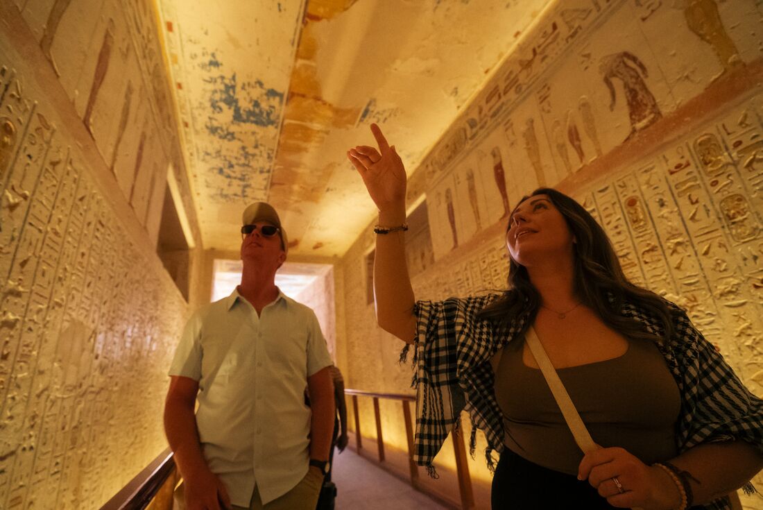 Traveller looking at hieroglyphic artwork on the walls at the Valley of the Kings, Luxor, Egypt