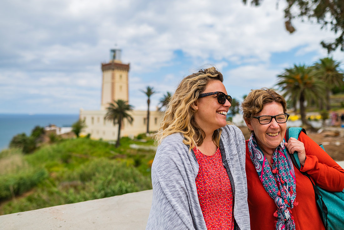 Travellers laughing with blue waters in background, Tangier, Morocco