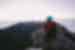 Female traveller in warm clothes sitting at the summit of Mount Kinabalu at sunrise in Borneo