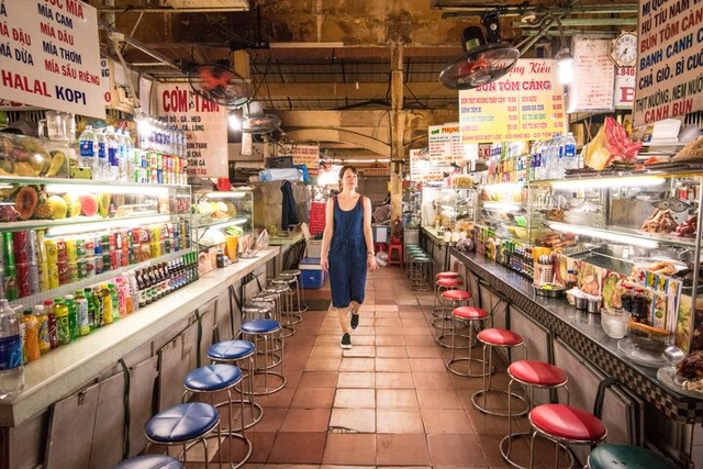 A solo female traveller walking through food stalls in the market in Ho Chi Minh City, Vietnam.