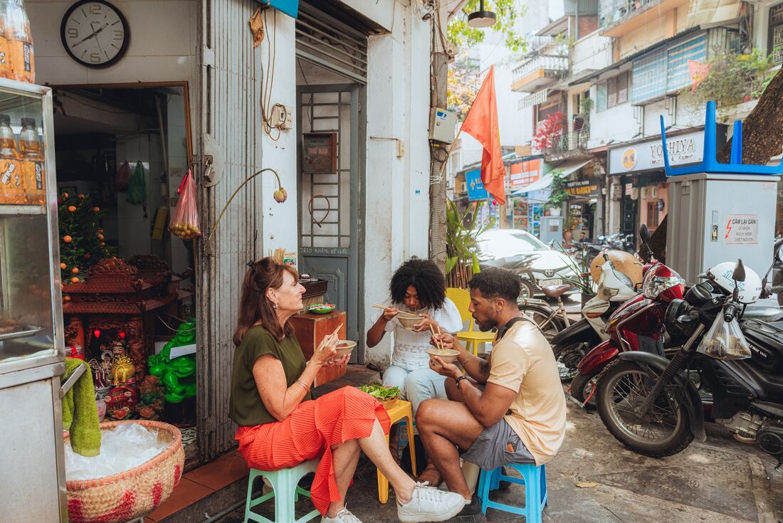 Travellers eating bun cha at local street restaurant in Hanoi, Vietnam