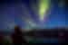Travellers looks out from the deck of the Ocean Explorer as northern lights dance over Greenland