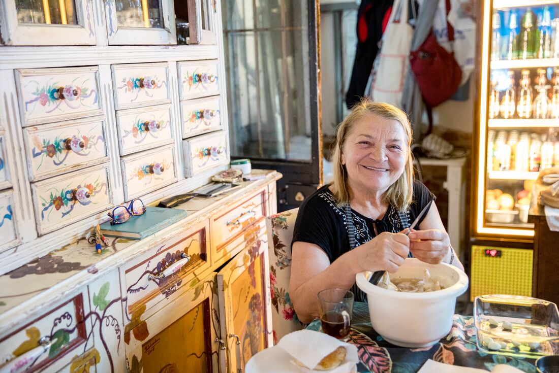 Chef smiles happily at the camera as she prepares food for lunch in a restaurant in Ayavalik