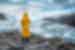 Traveller in a yellow raincoat standing on the rocks looking at Gullfoss Waterfall in Iceland