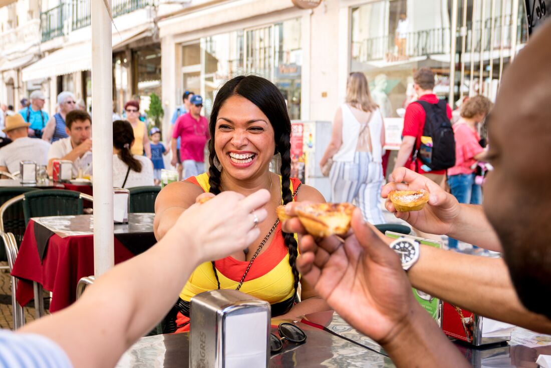 Sharing fresh pastel de nata, iconic Portuguese egg custard pastries, with travel group in Lisbon