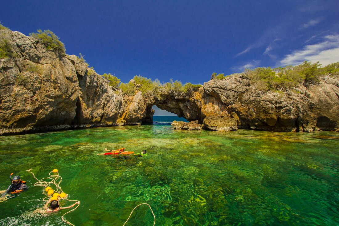 Travellers snorkeling clear waters in Koh Talu, Thailand