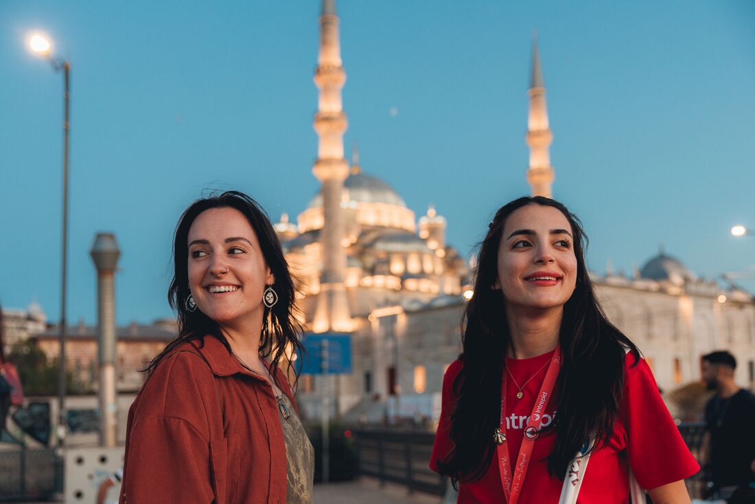 Smiling travellers with mosque behind them at dusk in Istanbul, Turkey