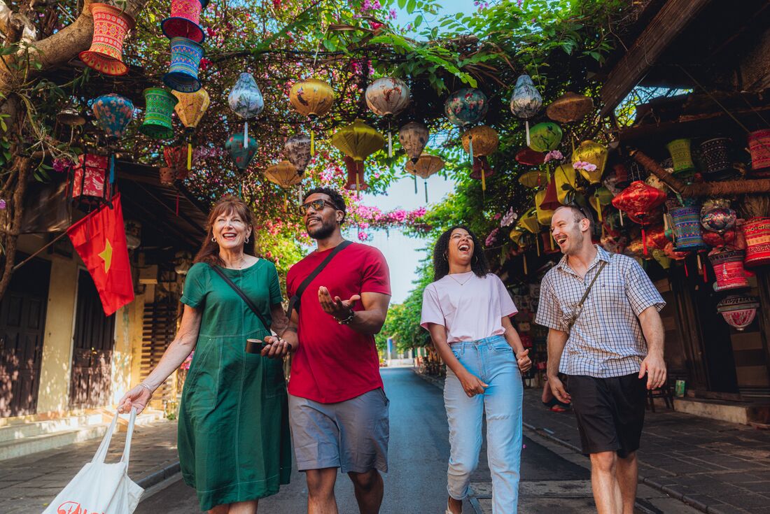 Travellers chatting and laughing as they walk through old city of Hoi An, Vietnam
