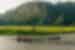 Wide shot of travellers and leader being guided on rowboats in the wide river valley of Van Long Nature Reserve