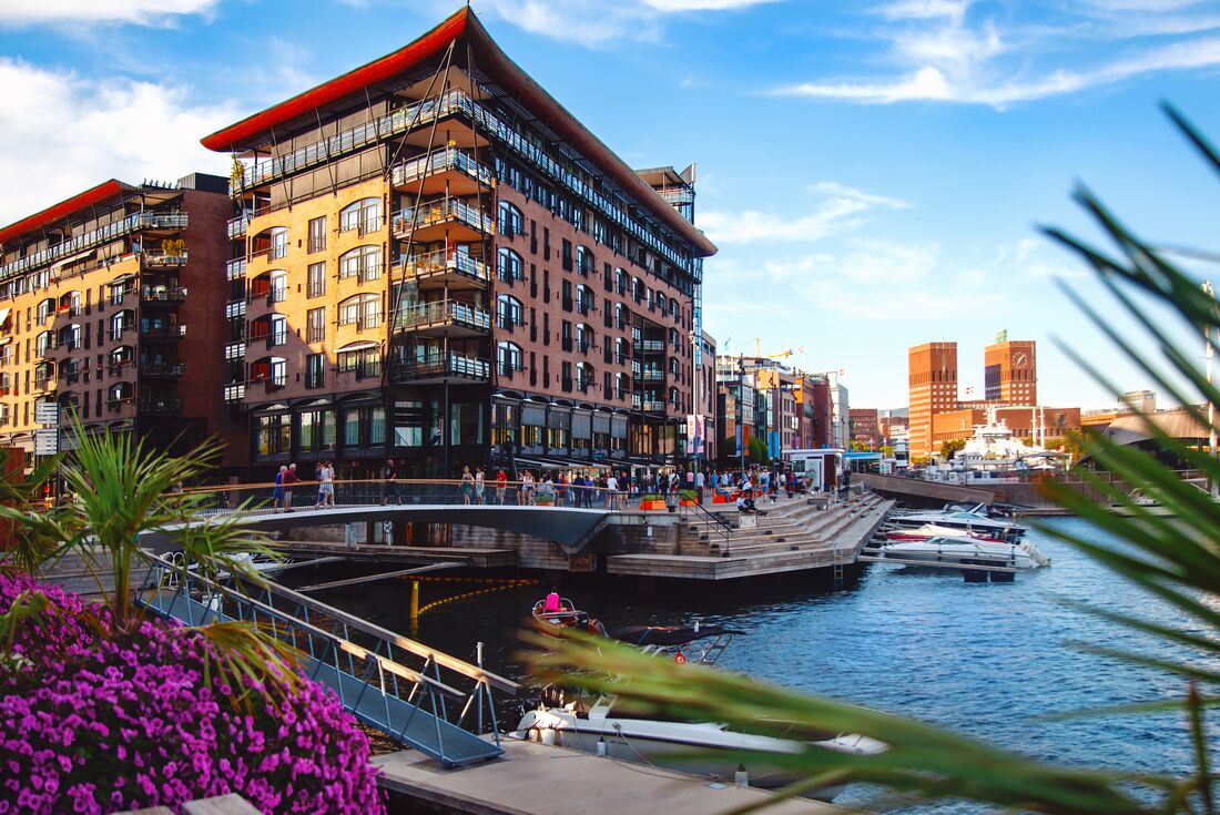 Oslo fjord harbour in the summer sun with locals going through waterfront businesses in Norway