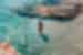 Traveller in swimsuit walks into crystal clear waters of the small Cyclades in Greece