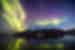 Yellow green and magenta waves of iridescent northern lights undulate over the Greenland landscape at twilight