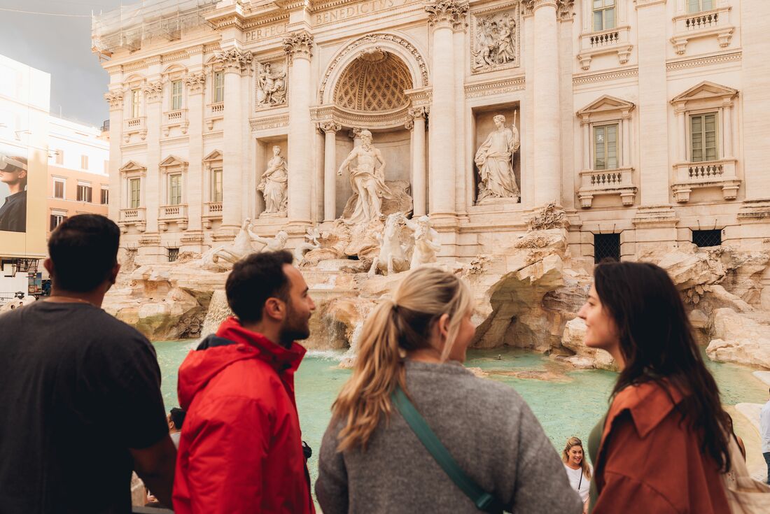 View from behind four travellers viewing the Trevi Fountain, Rome, Italy