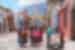 Locals walking around the colourful township of Antigua, Guatemala with a beautiful mountainous backgroup and blue sky.