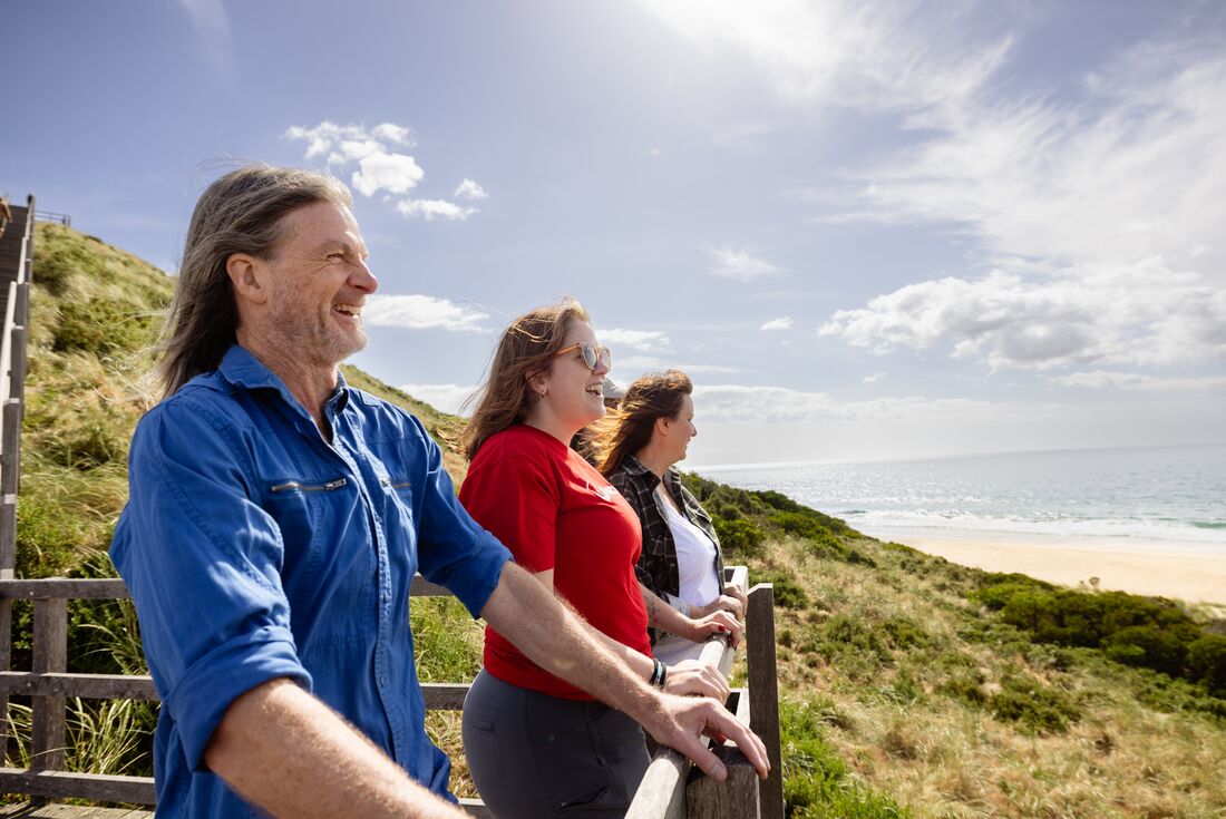 Smiling travellers enjoying the view of the beach and water at The Neck in Tasmania