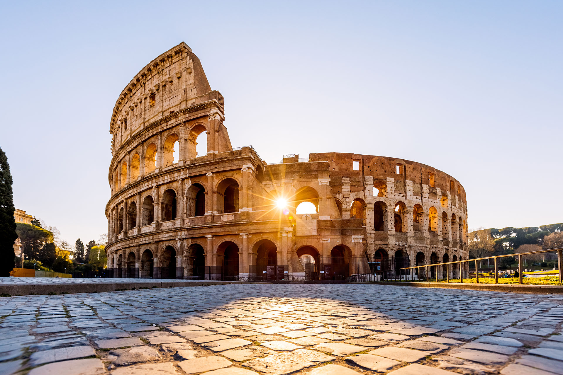 The Colosseum in Rome at sunrise with sunlight through the arches