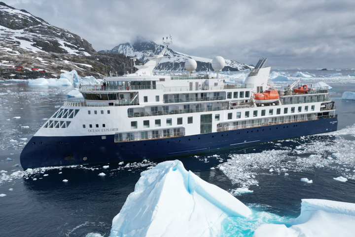 Ocean Explorer exterior from a distance with a large iceberg in the foreground