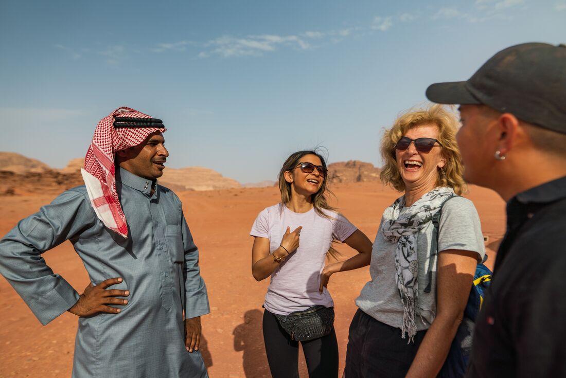 Travellers laughing with local guide in desert in  Wadi Rum, Jordan