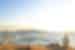Traveller perched on a high hill looks out over the sparkling Aegean and the island of Mykonos
