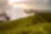 Grassy green volcanic hills with a plume of smoke rising at sunrise at Momacho Volcano Preserve in Nicaragua.