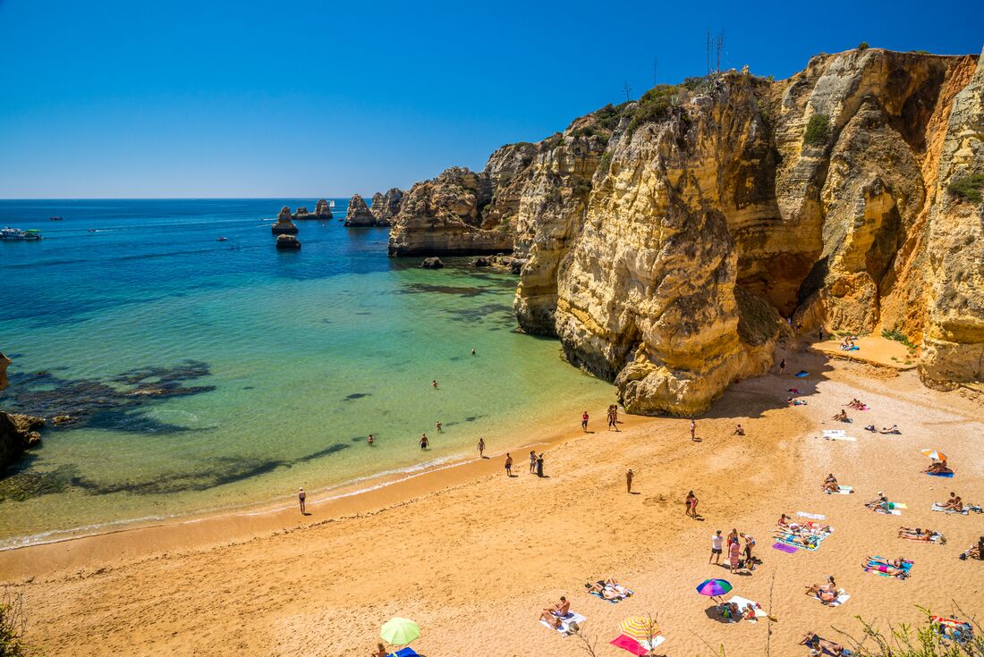 View of travellers gathered on Lagos Beach by thge cliff side, Portugal