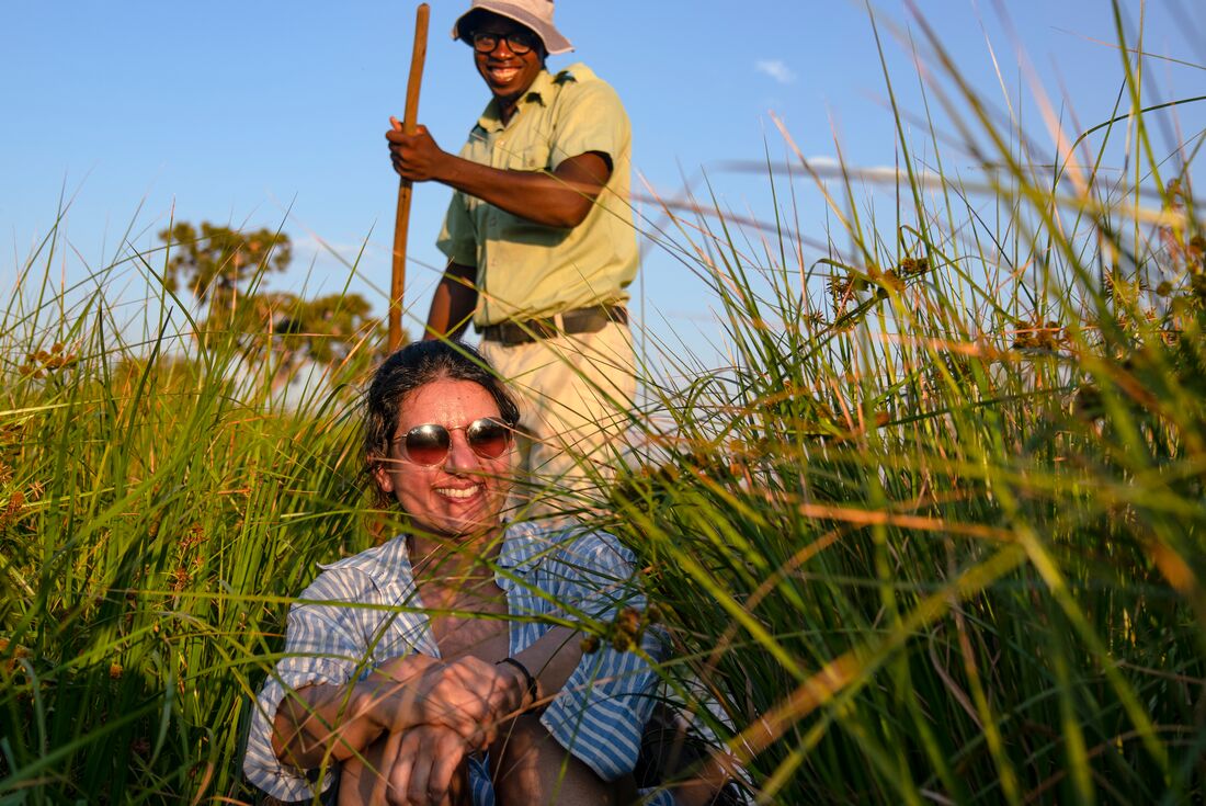 Traveller smiling as local guide takes her on a canoe ride on Okavango Delta, Botswana