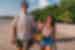 Young Intrepid travellers stroll along a beach in the Philippines with drinking coconuts laughing and enjoyng the sun