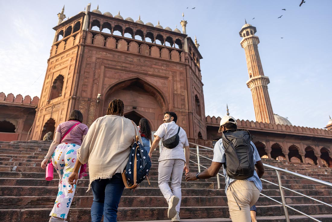The backs of travellers exploring around New Delhi with Jama Masjid mosque in background