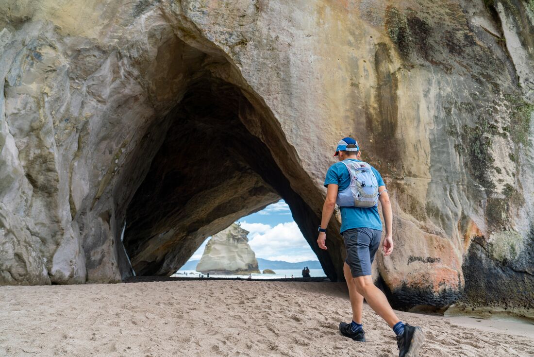 Traveller walking on the sand at Cathedral Cove in the Coromandel Peninsula, New Zealand