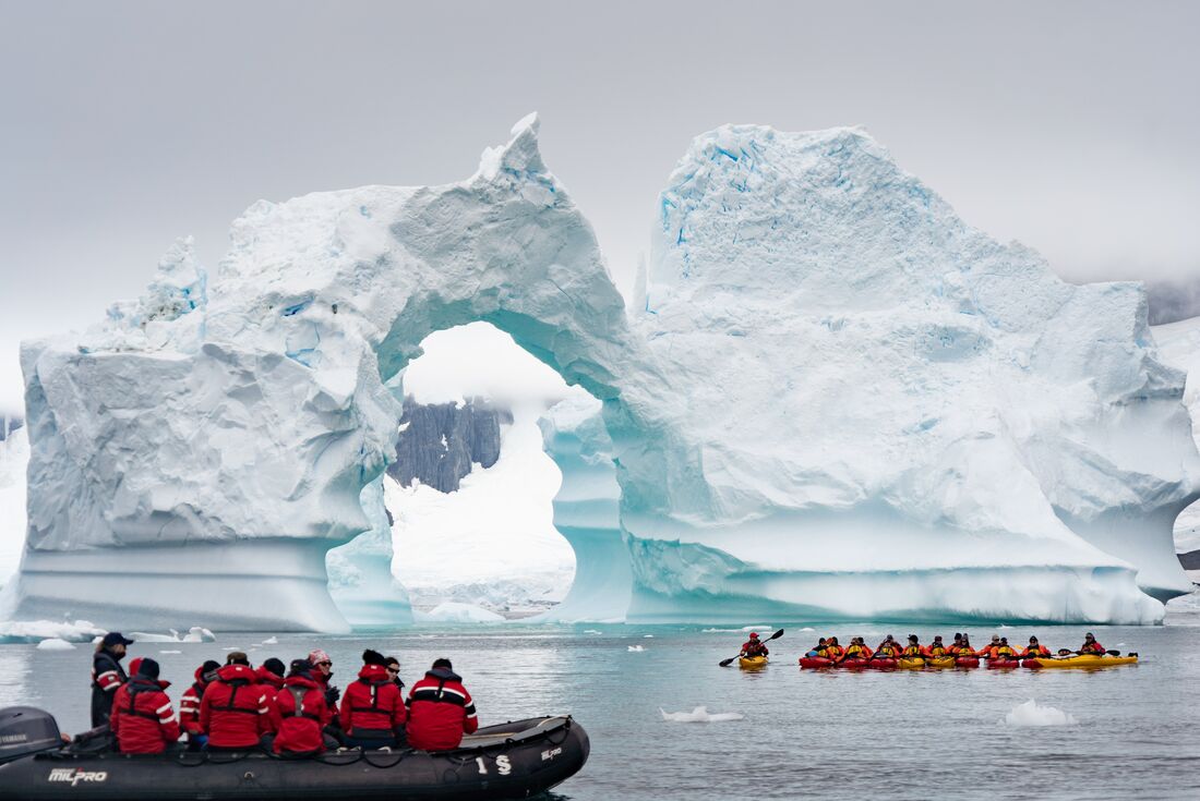 Everyone stops to take in the fragile scale of an arched iceberg off the Antarctic coast