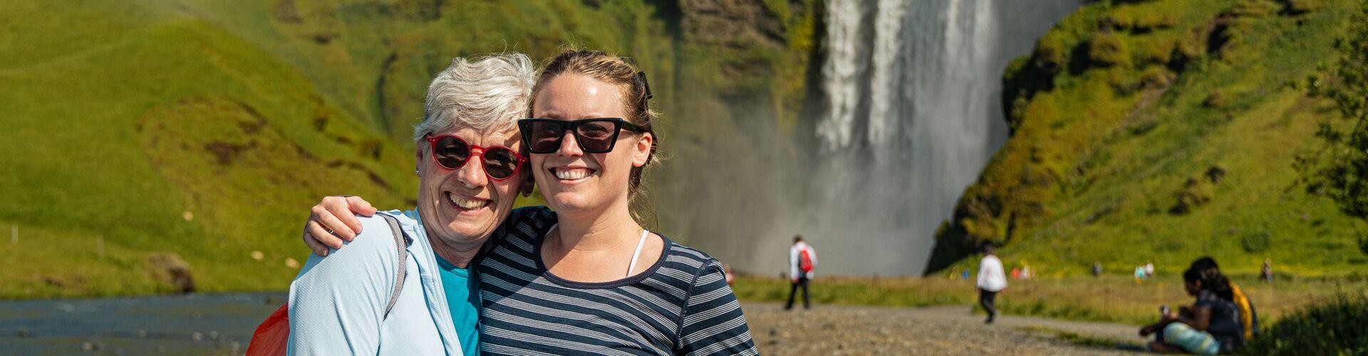 Two women posing in front of a waterfall