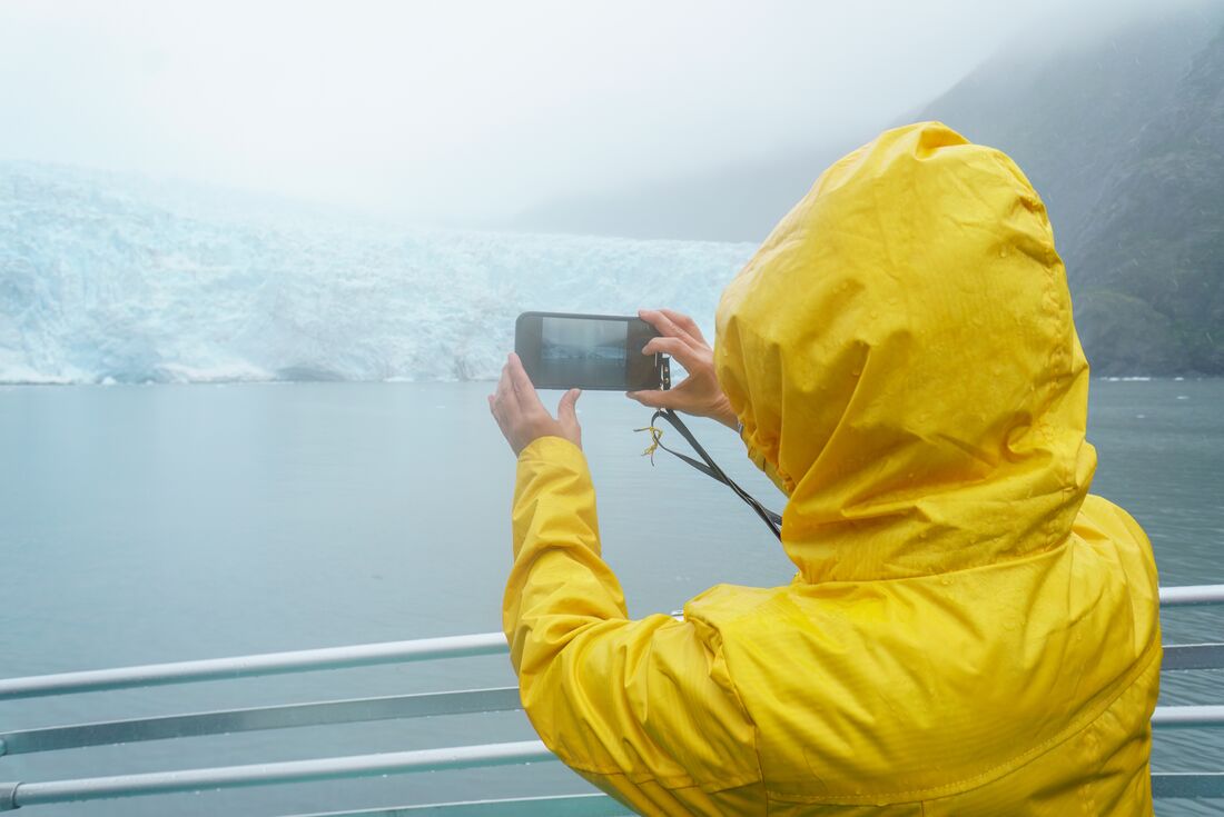 Traveller takes a photo of Holgate Glacier on their smartphone in Kenai Fjords, Alaska