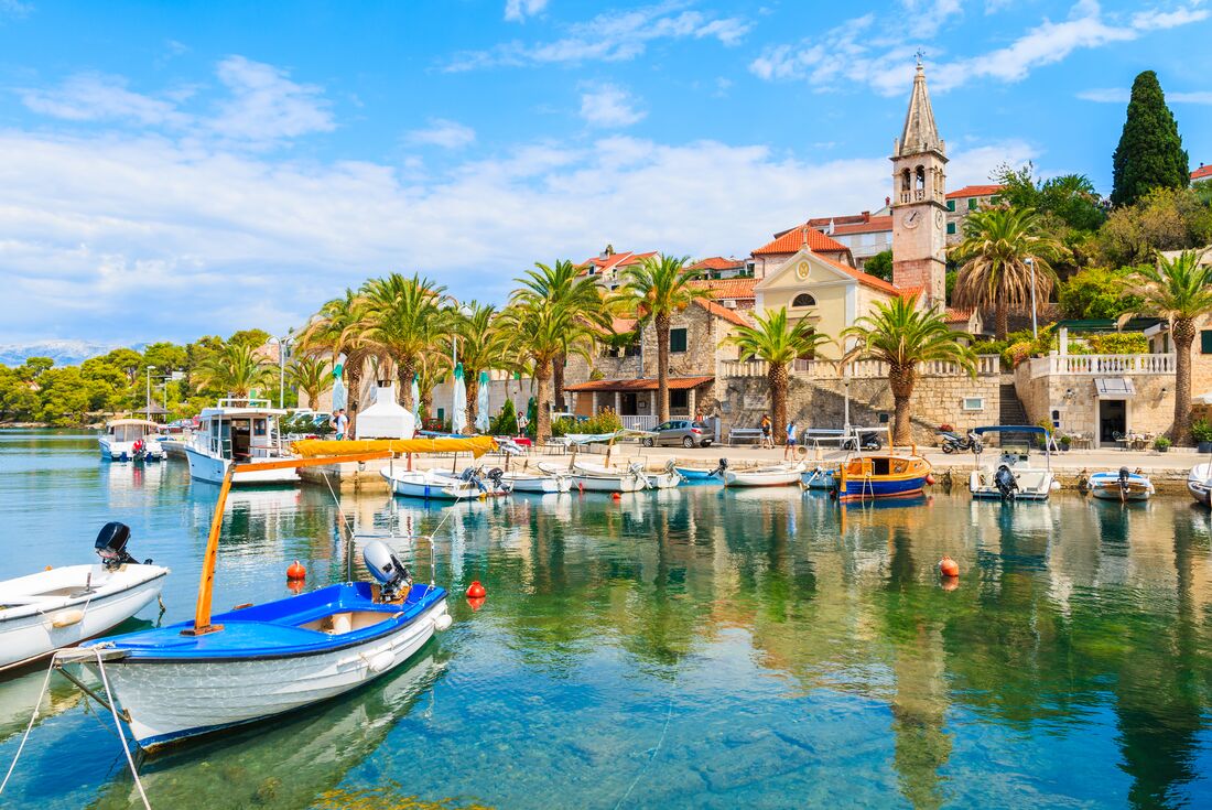 Scenic harbor and palm trees on Brac Island, Croatia coastal village waterfront
