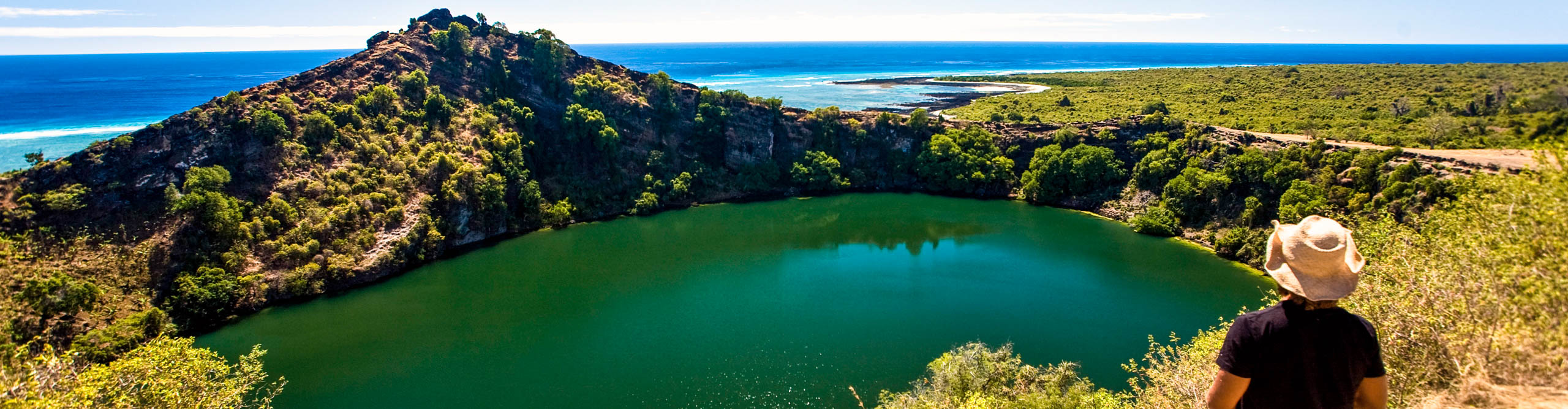 Woman Stanton on hill overlooking a lake near the beach on sunny day, Comoros Islands