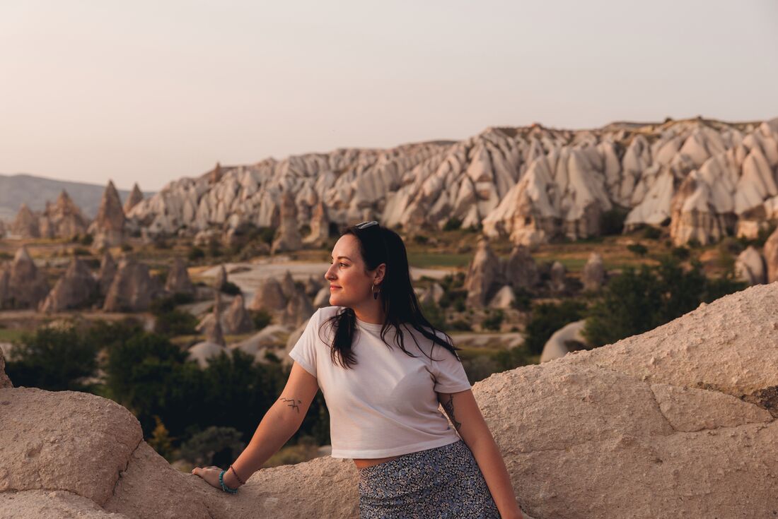 Traveller enjoying the view at sunset with rock formations in the valleys of Cappadocia, Turkey