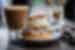An appetizing Semla bun with almonds and heavy cream, flour and sugar and a hot latte behind