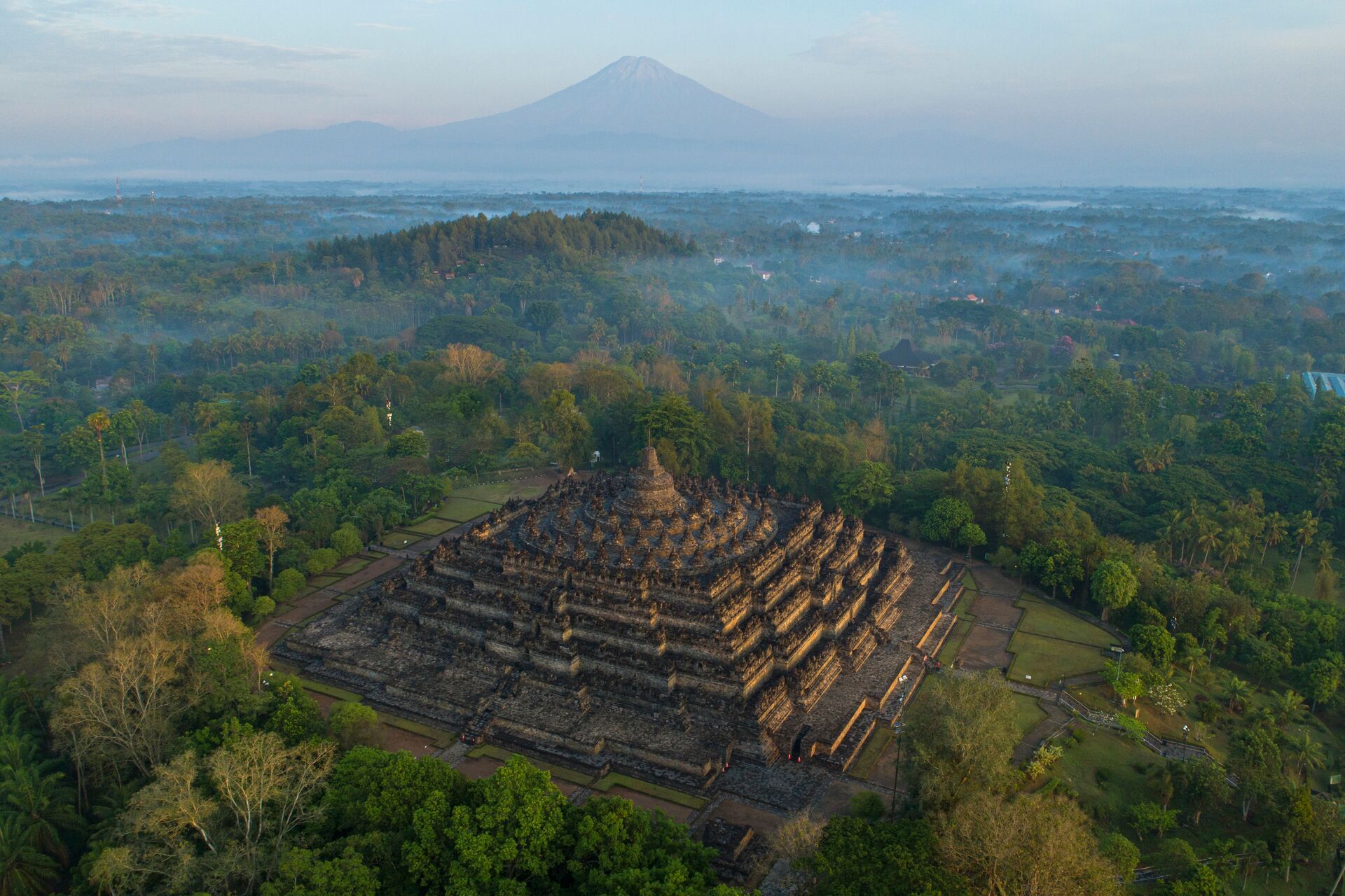 Borobudur Temple in the rainforests of Java, with Merapi volcano beyond