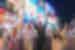 Intrepid travellers throw their hands up surrounded by screens and lights in Dotombori