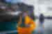 Traveller in bright yellow park hoodie looks up at island cliffs