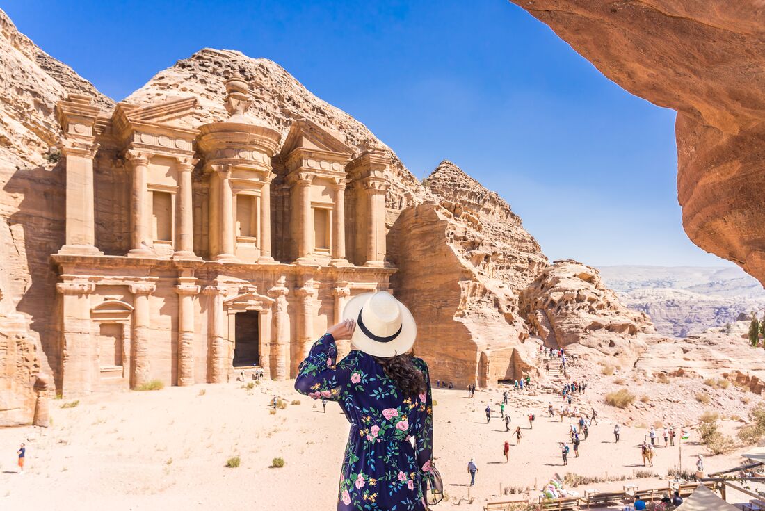 Traveller in a sun hat enjoying the majestic view of the Monastery monument in City of Petra, Jordan