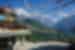 Intrepid traveller in a small mountainside plaza with prayer flags strung between buildings and Annapurna mountains in the distance.