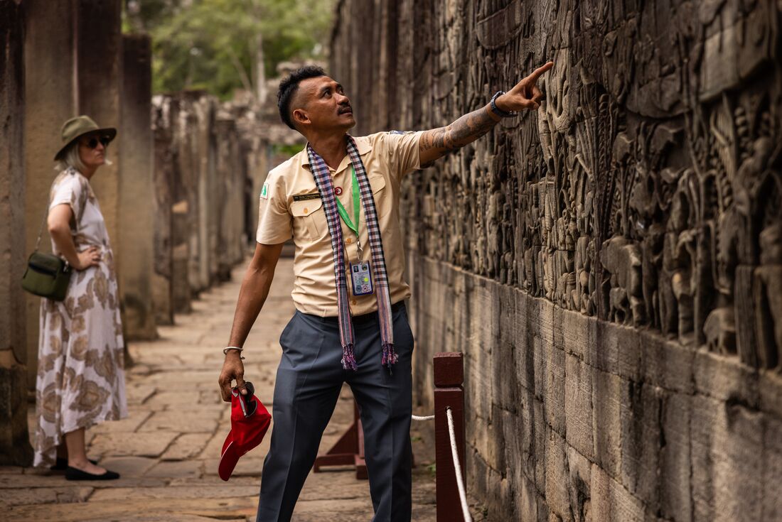 Leader pointing at wall art on the walls of Angkor Wat, Siem Reap, Cambodia