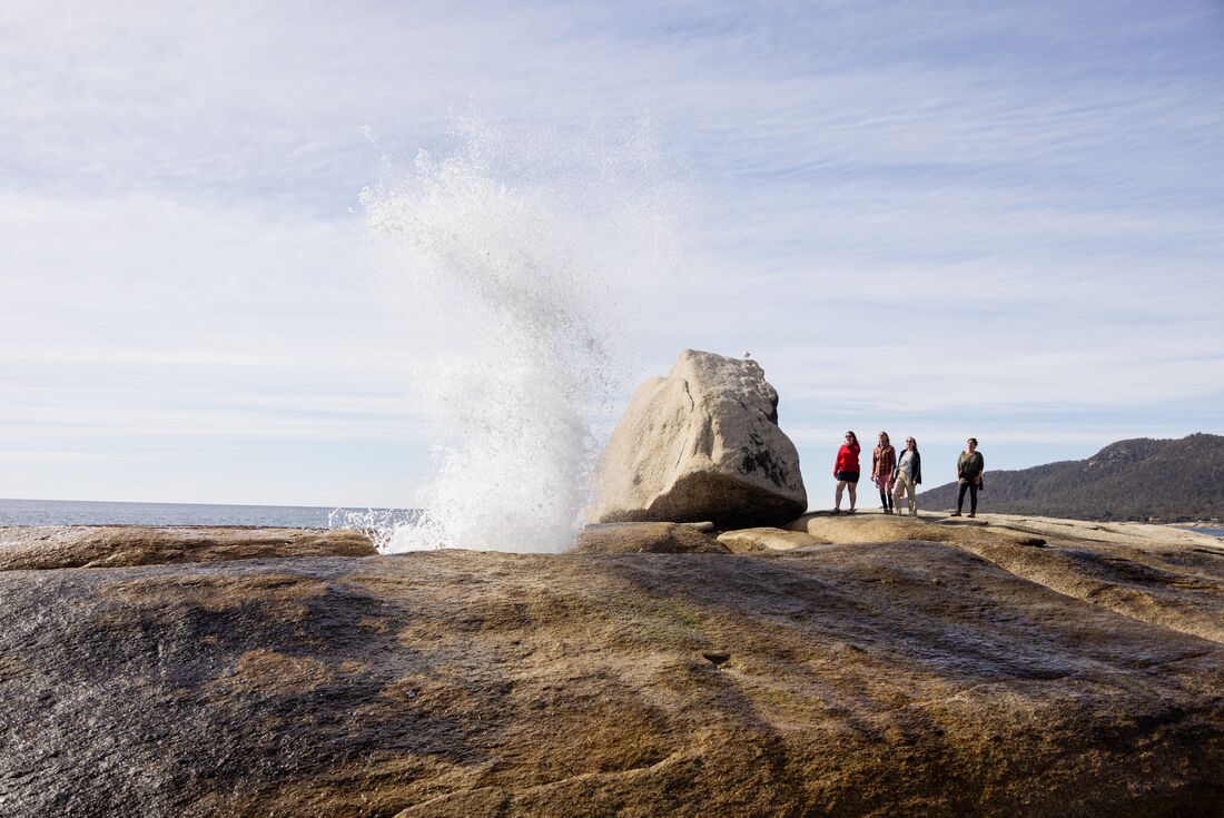Travellers observing water erupting from Bicheno Blowhole, Tasmania, Australia