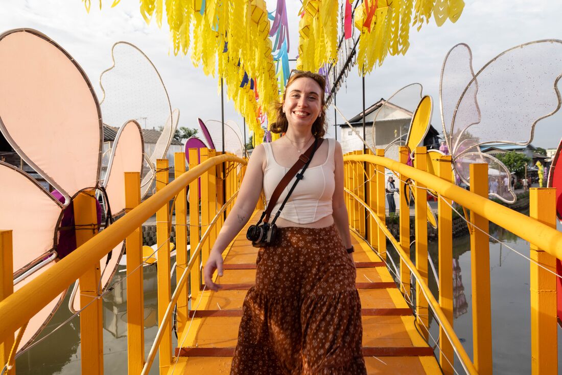Smiling traveller walks on a yellow bridge over a canal in Chiang Mai, Thailand