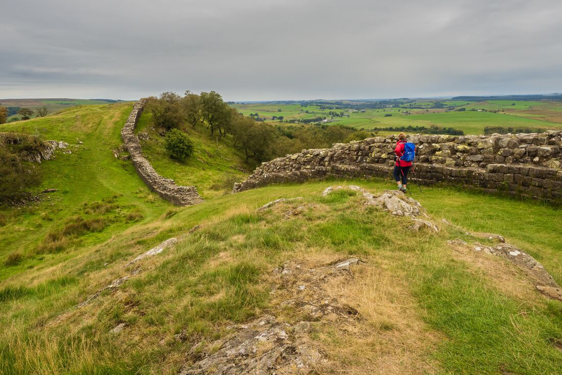 Distant view of Female traveller walking along Hadrian's Wall on a gloomy day in England, U.K.