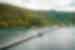 Wide view of bridge crossing the water to Yenbuba Village and mountainous forest background in Indonesia