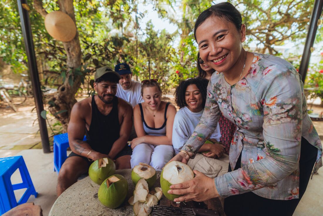 Local guide showing travellers fresh coconut produce by the Mekong Delta, Vietnam
