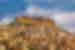City of Mardin with ancient minarets and buildings climbs a hill to towering stone top with hawk flying in Turkey