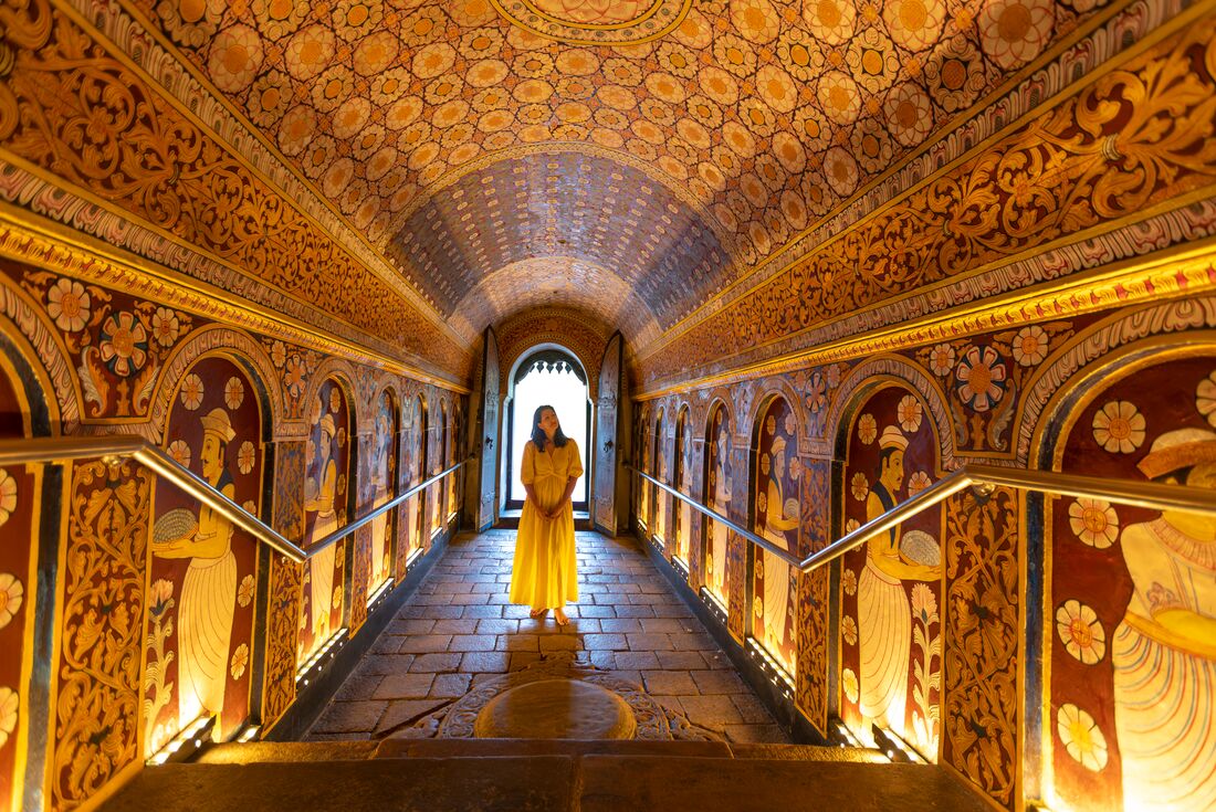 Intrepid traveller looking around at elaborately painted interior of Temple of the Sacred Tooth in Sri Lanka